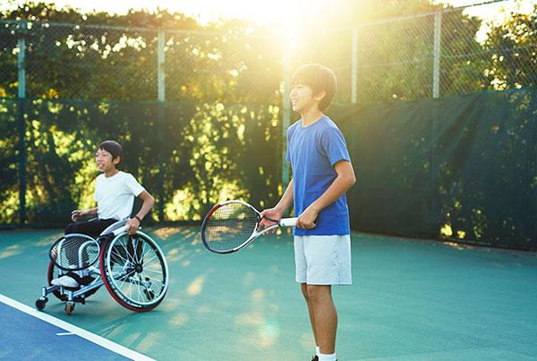 坐在轮椅上打网球的少年